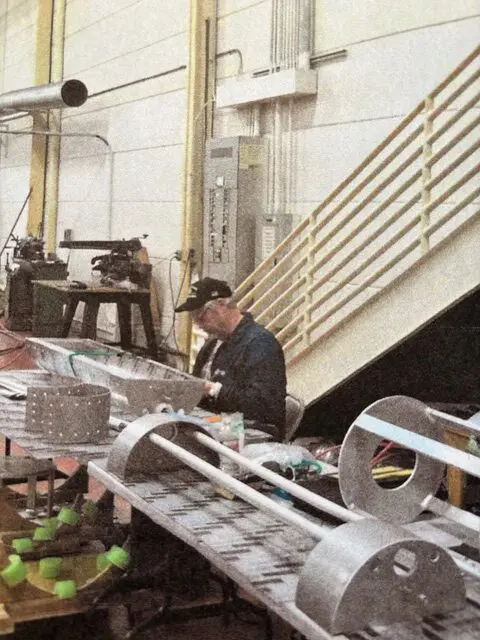 A worker assembling metal parts in an industrial workshop.