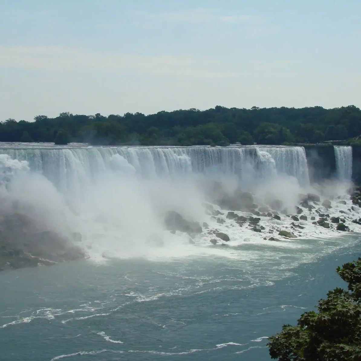 Mist rises from the powerful waterfall surrounded by greenery.