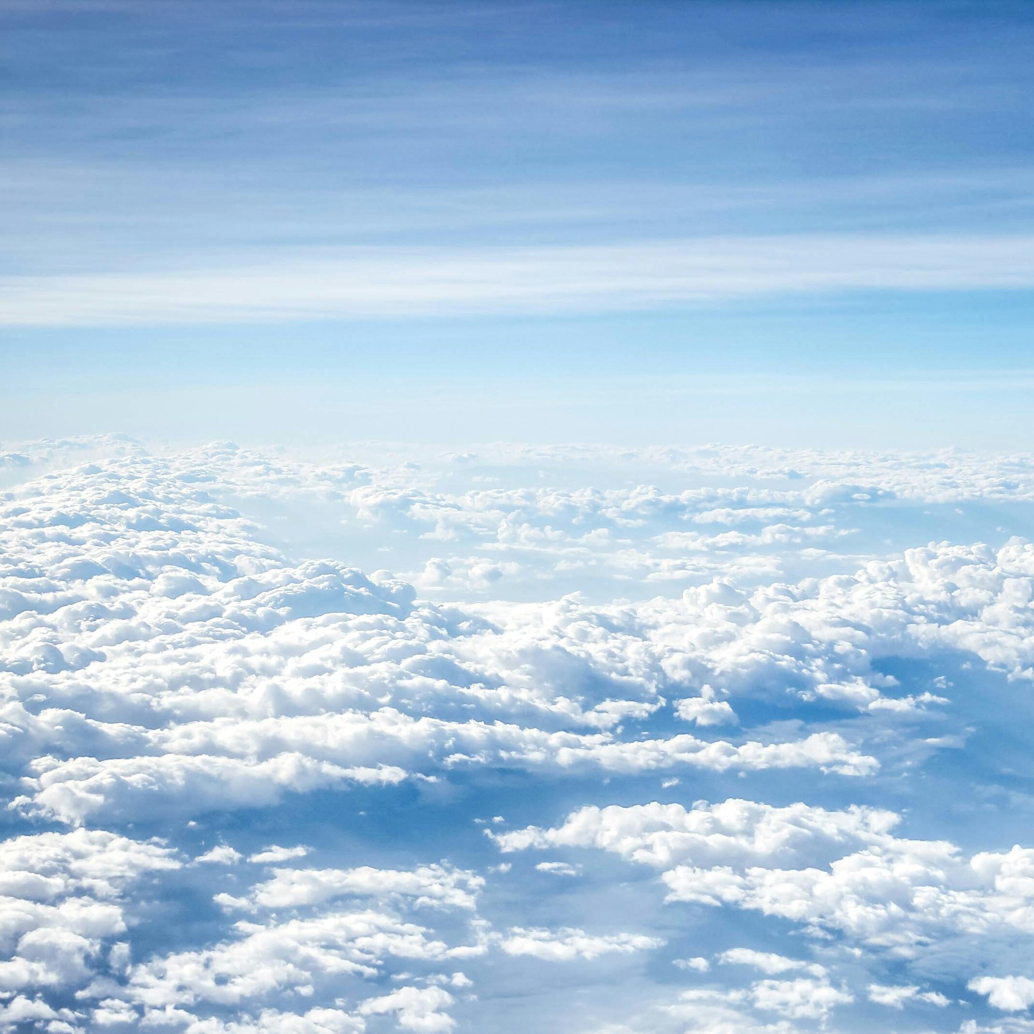 Aerial view of fluffy white clouds under a clear blue sky.